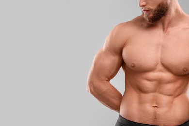 Muscular man showing abs on light grey background, closeup and space for text. Sexy body