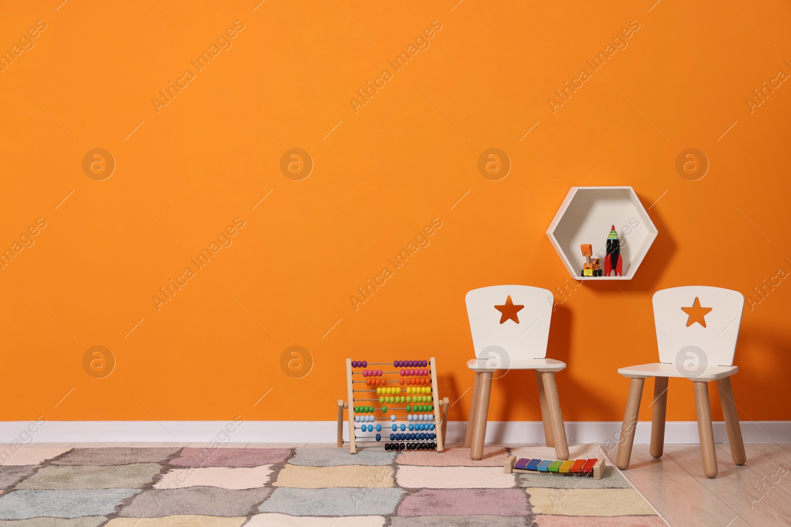 Photo of Beautiful children's room with bright orange wall and furniture, space for text. Interior design