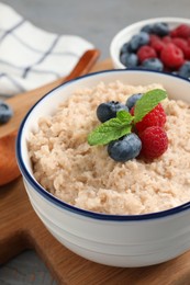 Photo of Tasty oatmeal porridge with berries on grey wooden table, closeup