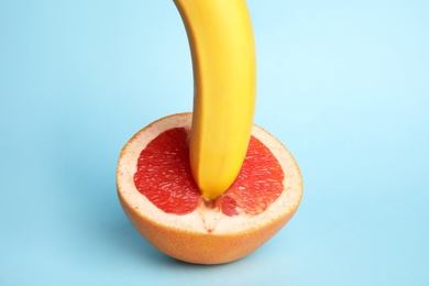 Photo of Fresh grapefruit and banana on blue background. Sex concept