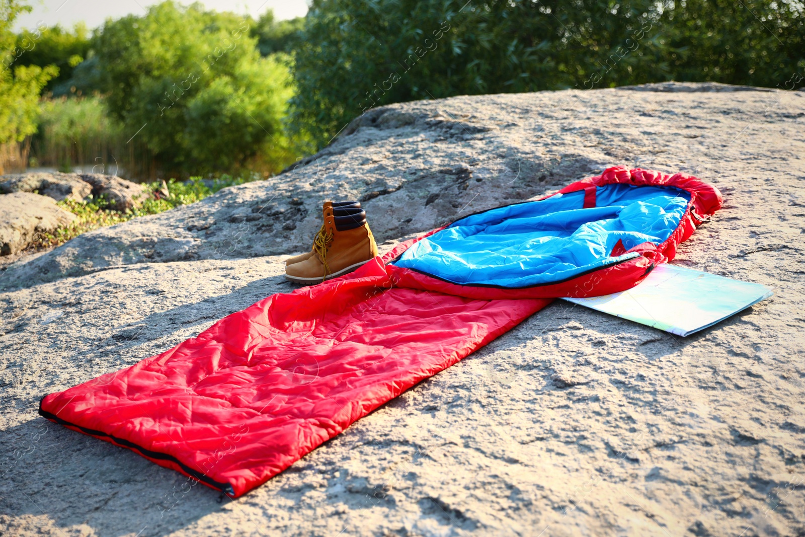 Photo of Sleeping bag, boots and map outdoors on sunny day