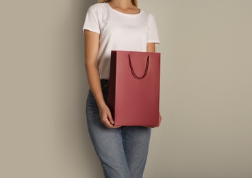 Photo of Woman with paper shopping bag on light grey background, closeup