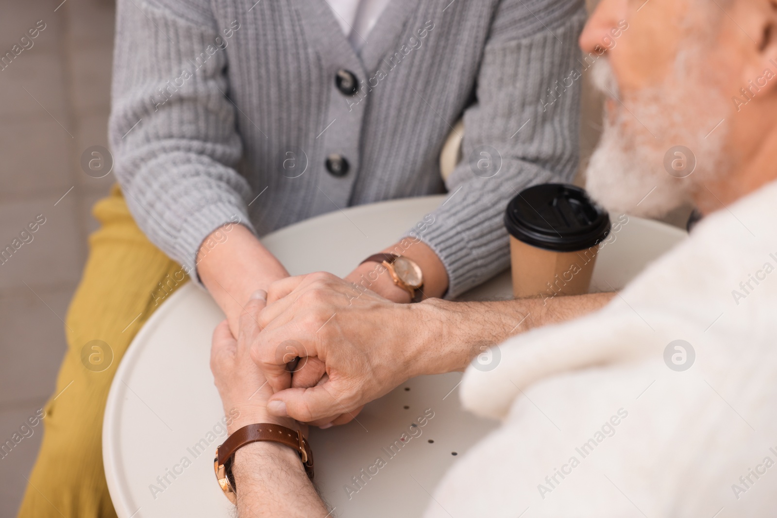 Photo of Affectionate senior couple sitting at table outdoors, closeup