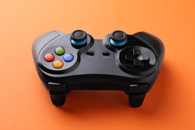 Photo of One wireless game controller on orange background