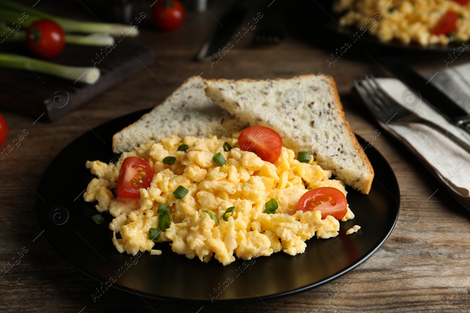 Photo of Tasty scrambled eggs with cherry tomato and bread on wooden table