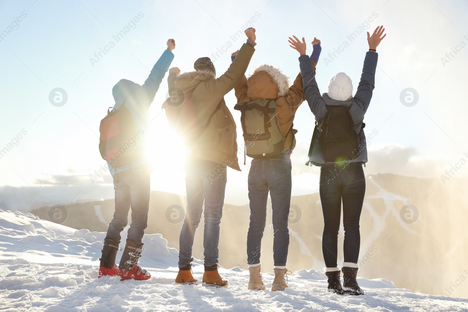 Photo of Group of excited friends with backpacks enjoying mountain view during winter vacation