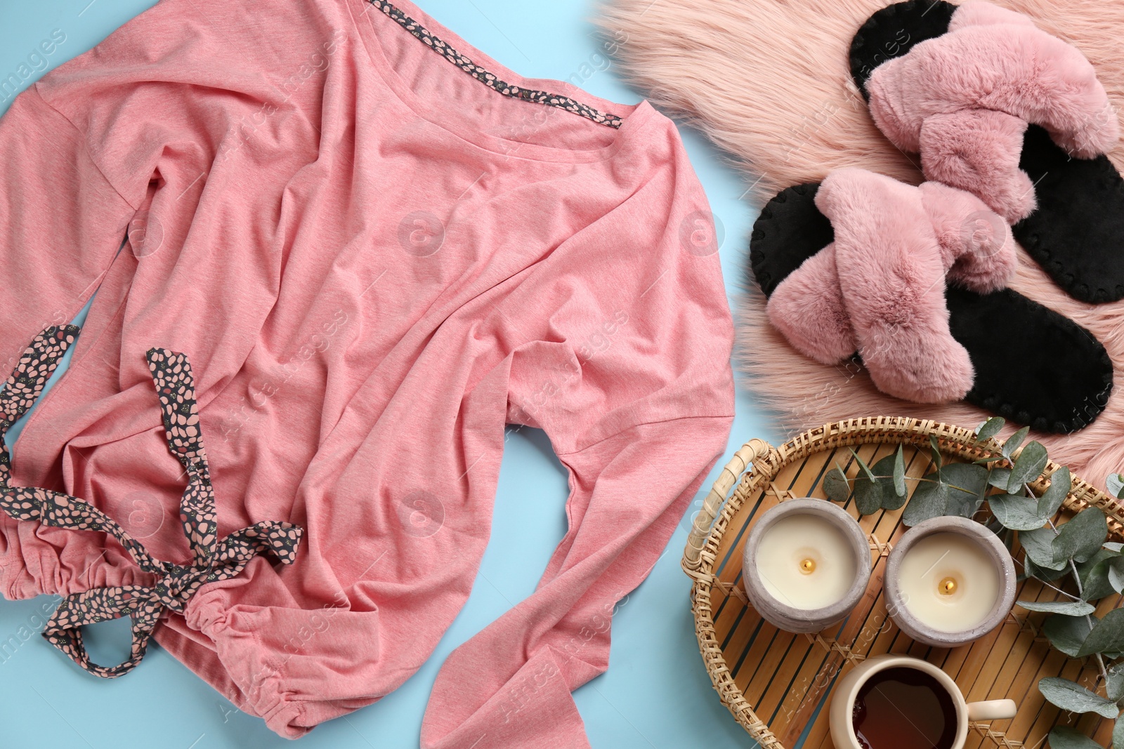 Photo of Flat lay composition with fluffy slippers and pajamas on light blue background. Comfortable home outfit