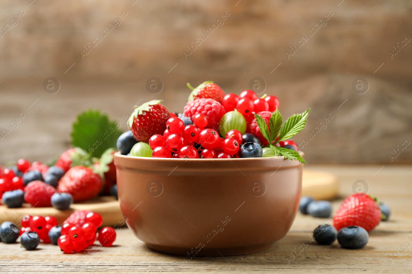 Photo of Mix of different fresh berries in bowl on wooden table