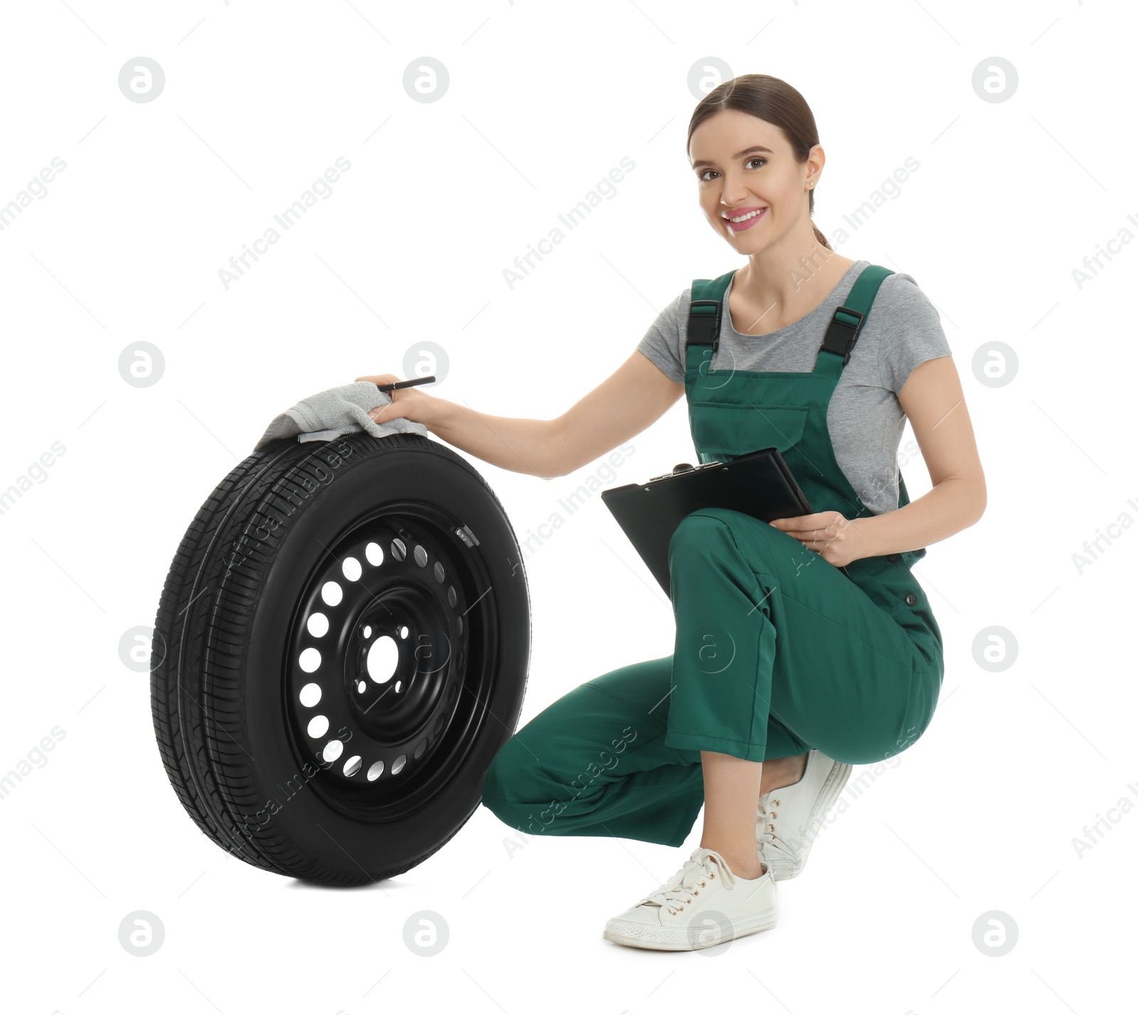 Photo of Professional auto mechanic with wheel and clipboard on white background