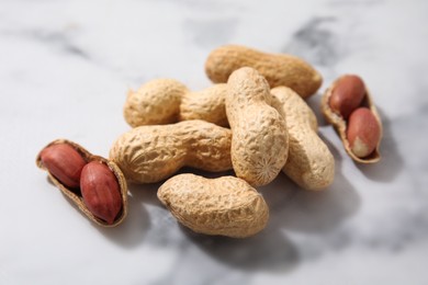 Fresh unpeeled peanuts on white marble table, closeup