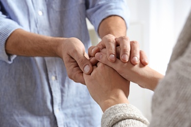 Man comforting woman on light background, closeup of hands. Help and support concept