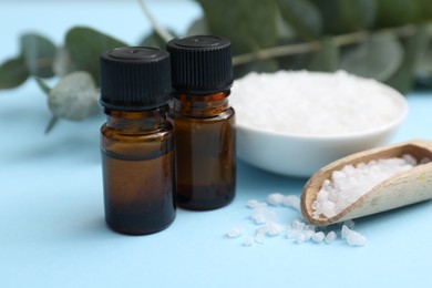 Photo of Aromatherapy products. Bottles of essential oil and sea salt on light blue table, closeup