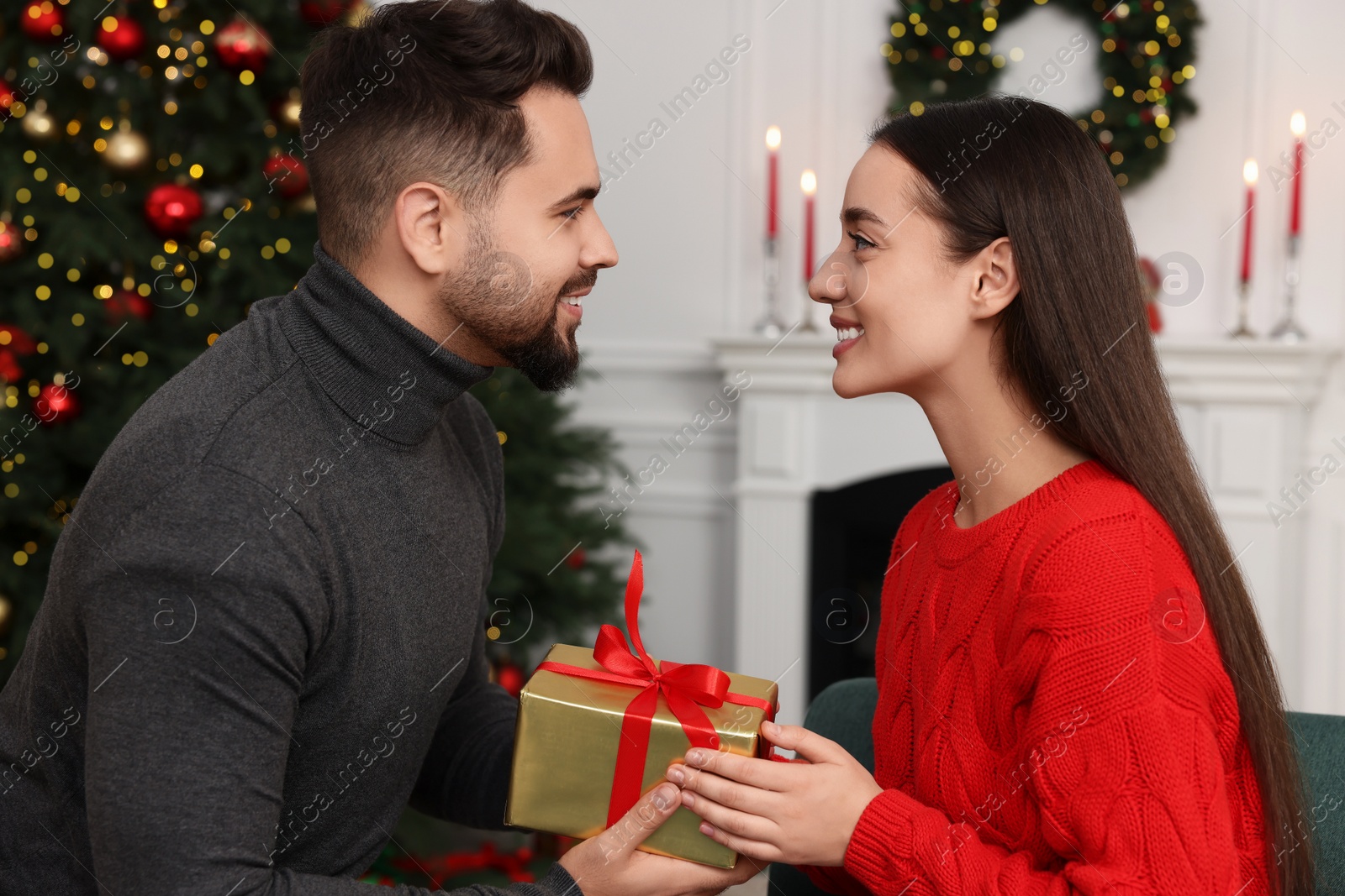 Photo of Happy man giving Christmas gift to his girlfriend at home