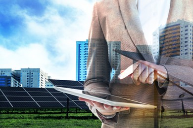 Image of Double exposure of businesswoman with tablet and solar panels installed outdoors. Alternative energy source