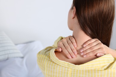 Photo of Woman suffering from neck pain indoors, closeup