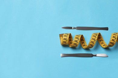 Photo of Scalpels and measuring tape on light blue background, flat lay with space for text. Weight loss surgery