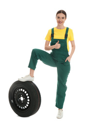 Photo of Full length portrait of professional auto mechanic with wheel on white background