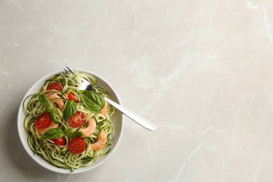 Photo of Delicious zucchini pasta with shrimps, cherry tomatoes  and basil on light grey table, top view. Space for text