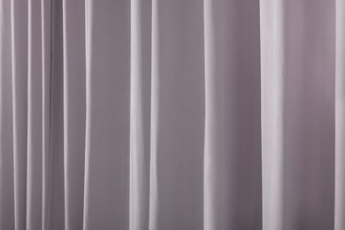 Photo of Beautiful light grey window curtains as background, closeup