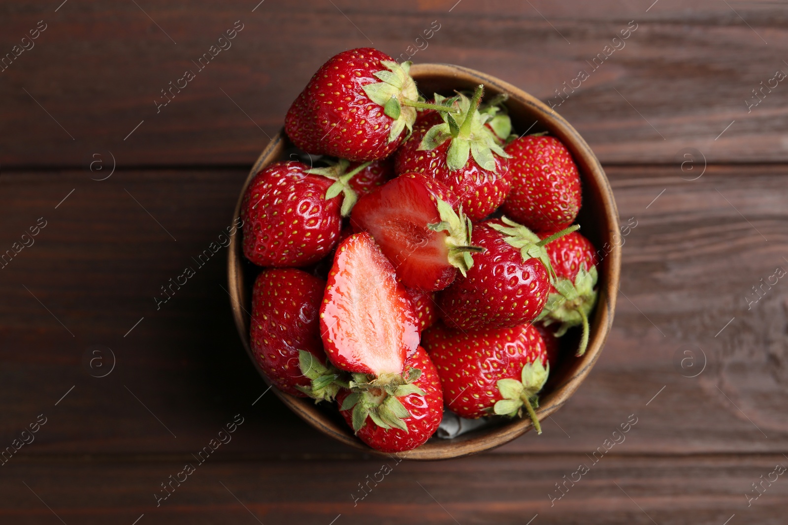 Photo of Delicious ripe strawberries in bowl on wooden table, top view