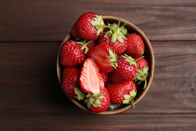 Delicious ripe strawberries in bowl on wooden table, top view