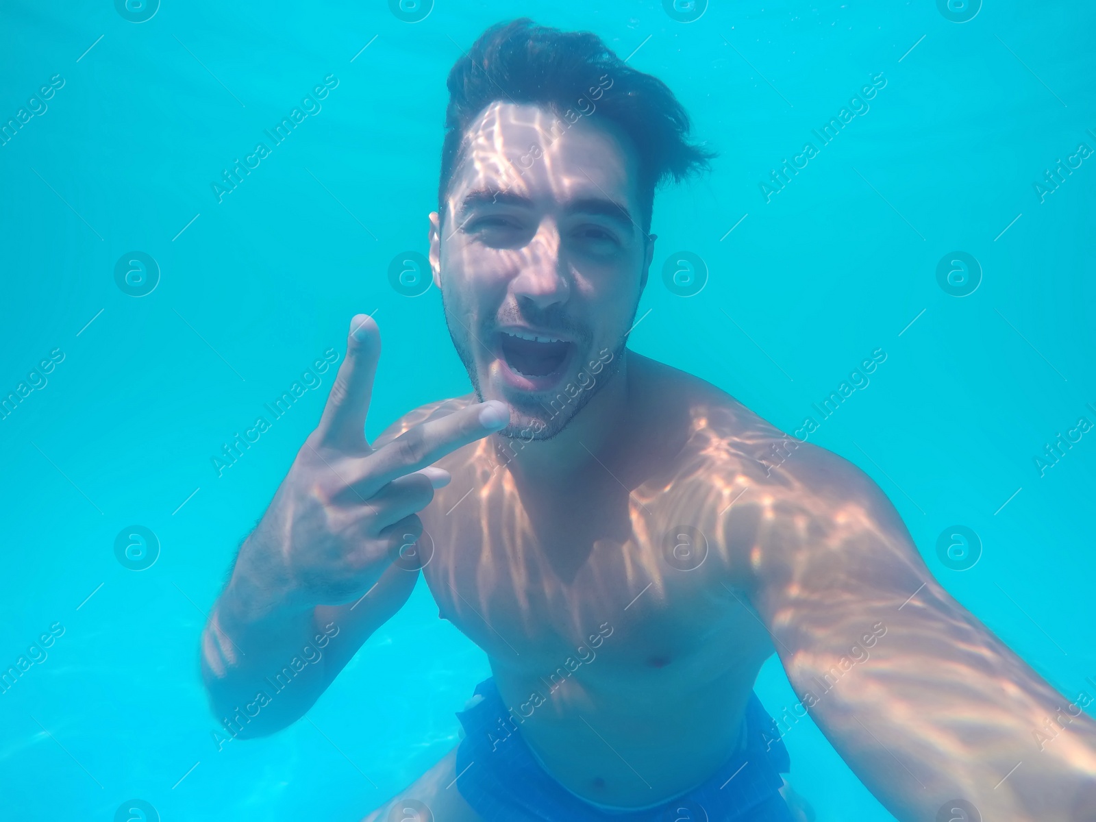 Photo of Handsome young man swimming in pool, underwater view