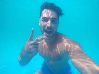 Handsome young man swimming in pool, underwater view