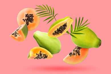 Image of Fresh papaya fruits and green leaves falling on pink background