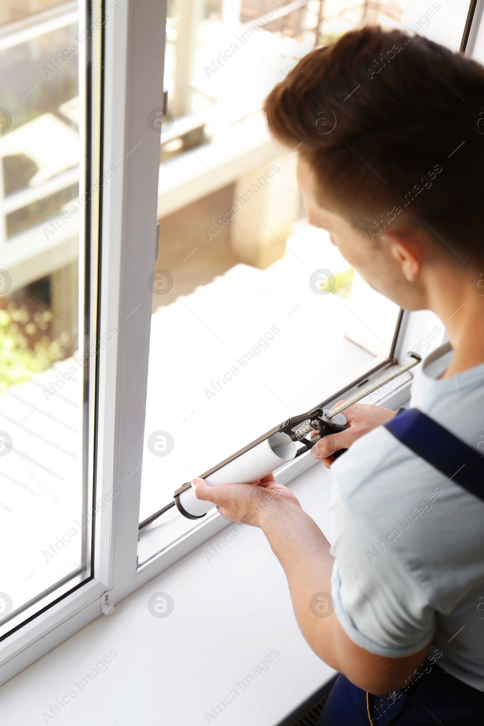 Photo of Construction worker sealing window with caulk indoors