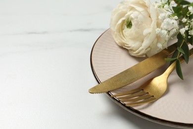 Photo of Stylish table setting with cutlery and flowers on white marble background, closeup. Space for text