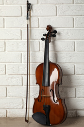 Photo of Classic violin and bow near white brick wall