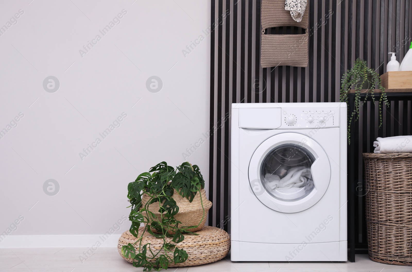 Photo of Laundry room interior with washing machine and houseplants. Space for text