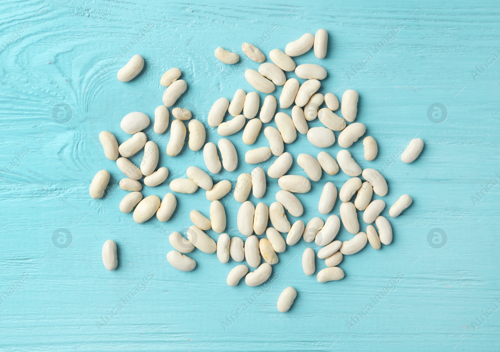 Photo of Raw beans on light blue wooden background, flat lay. Vegetable seeds