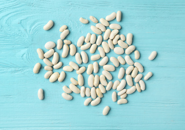 Raw beans on light blue wooden background, flat lay. Vegetable seeds