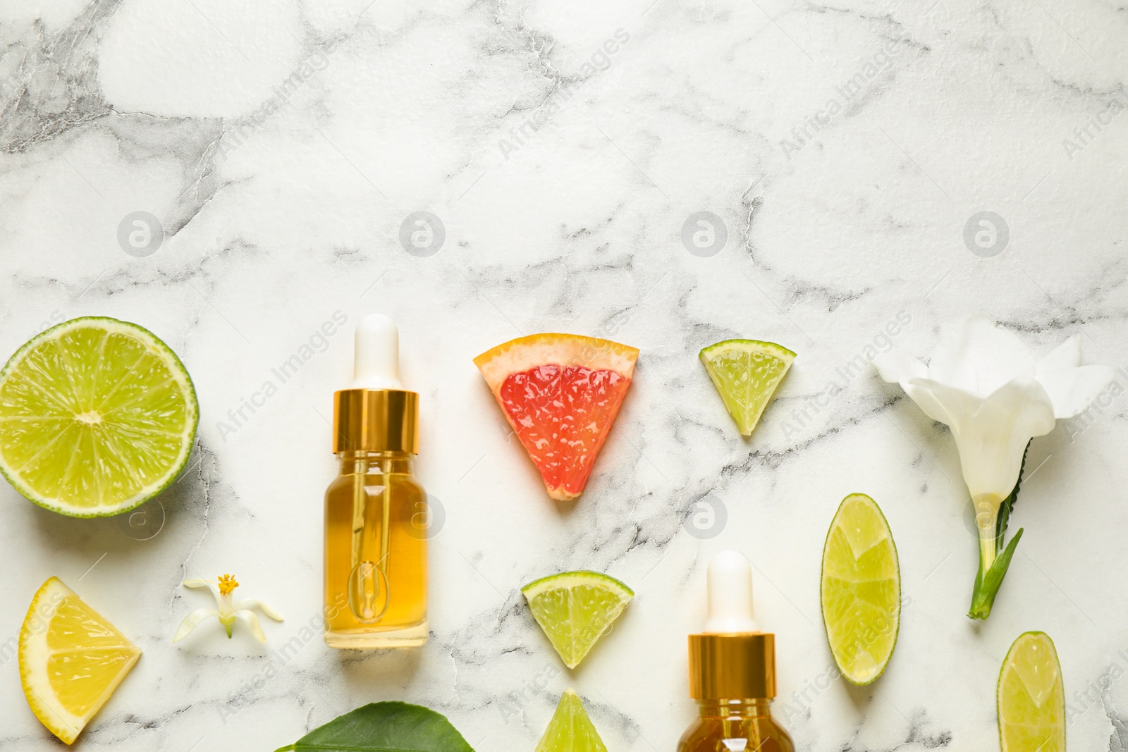 Photo of Flat lay composition with bottles of citrus essential oil on white marble background. Space for text