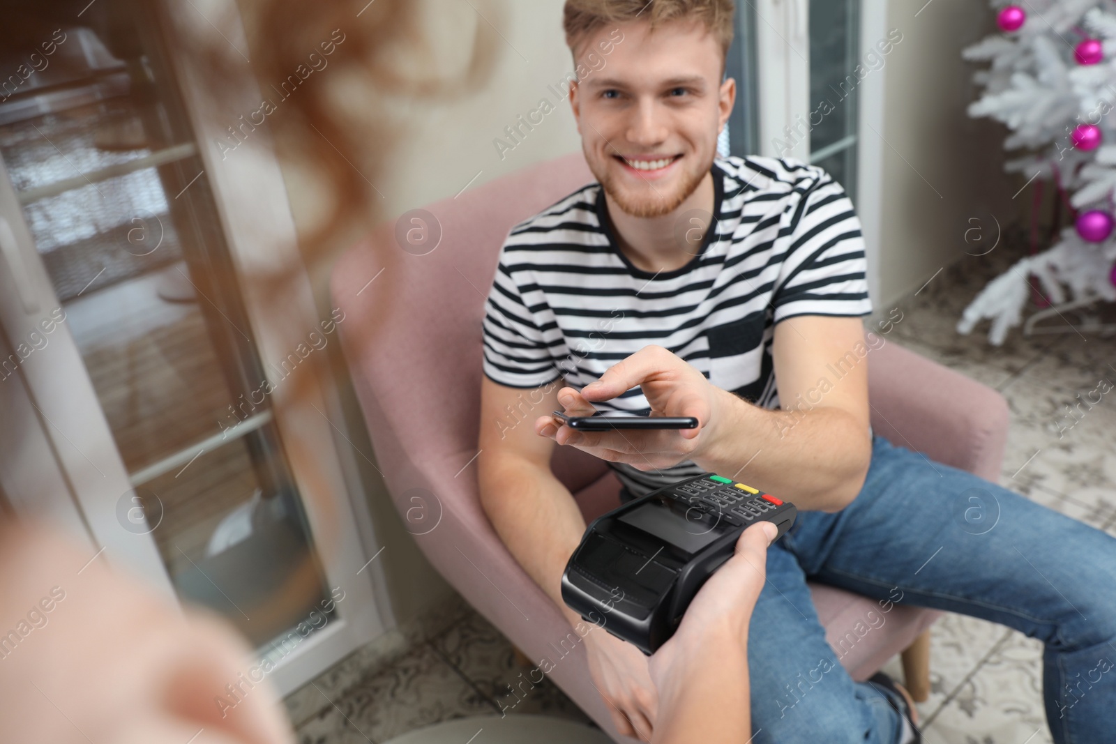 Photo of Client using smartphone and credit card machine for non cash payment in cafe