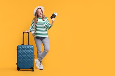 Happy young woman with passport, ticket, hat and suitcase on yellow background, space for text