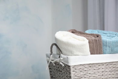 Basket with soft bath towels against blurred background. Space for text