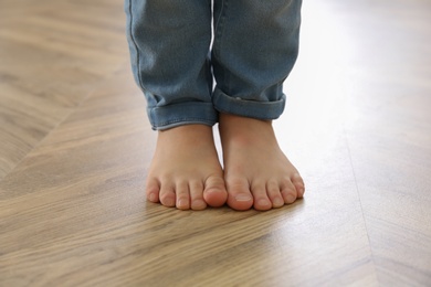 Photo of Little child walking barefoot at home, closeup. Floor heating concept