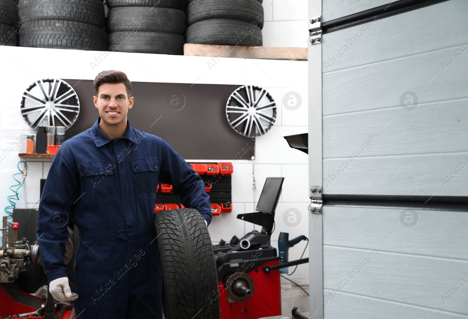Photo of Professional worker with wheel in shop of modern tire service