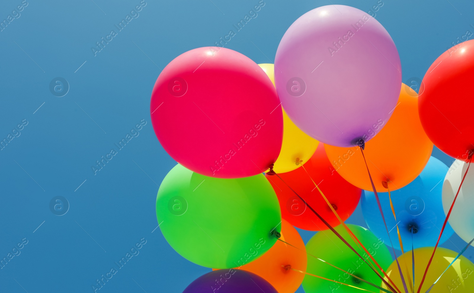 Photo of Woman with bunch of colorful balloons against blue sky