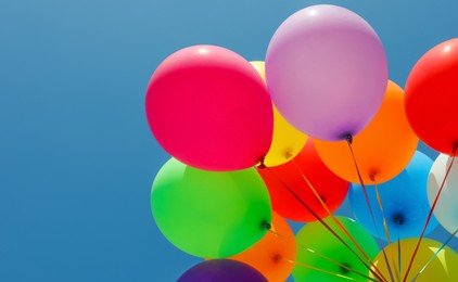 Woman with bunch of colorful balloons against blue sky
