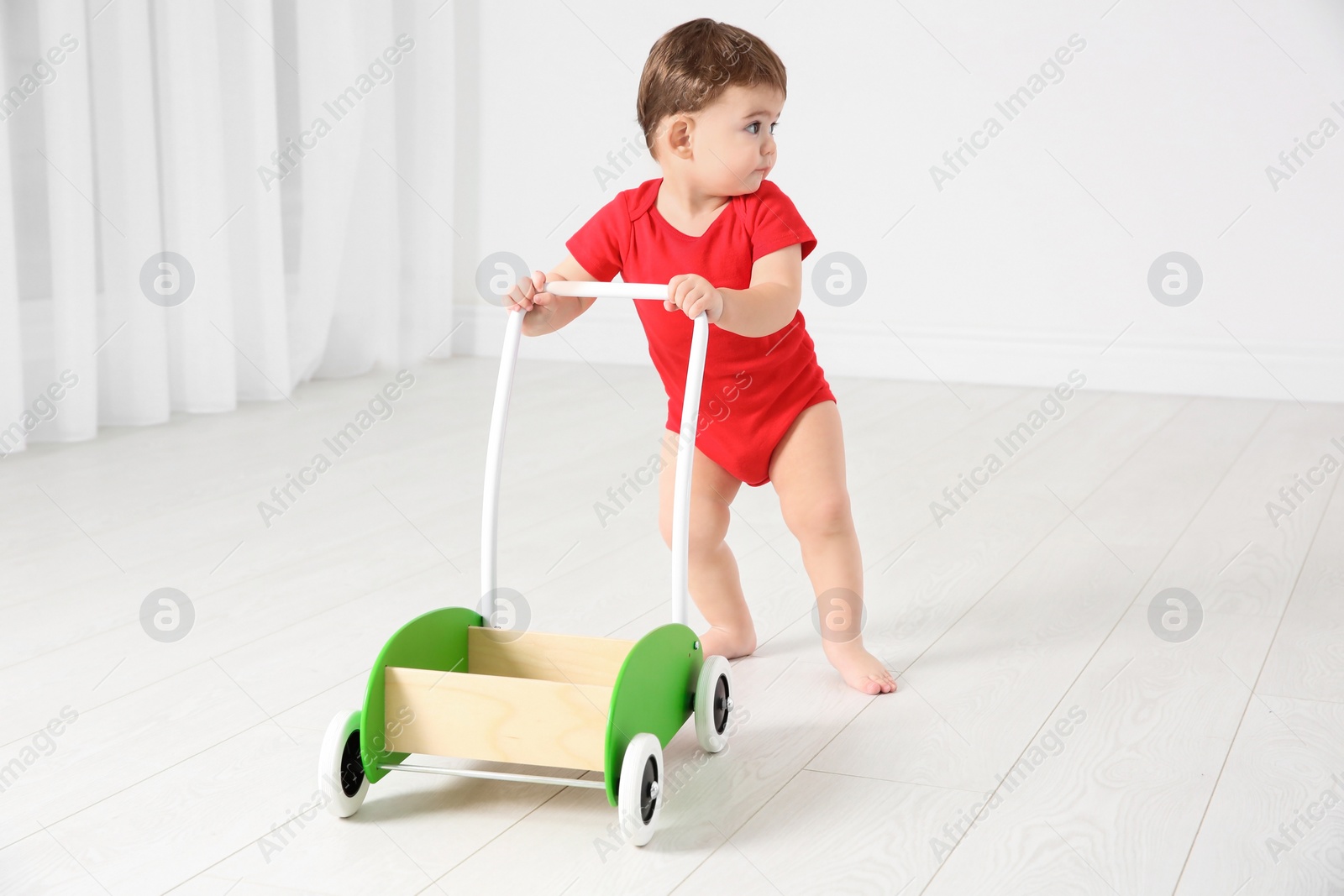 Photo of Cute baby playing with toy walker, indoors