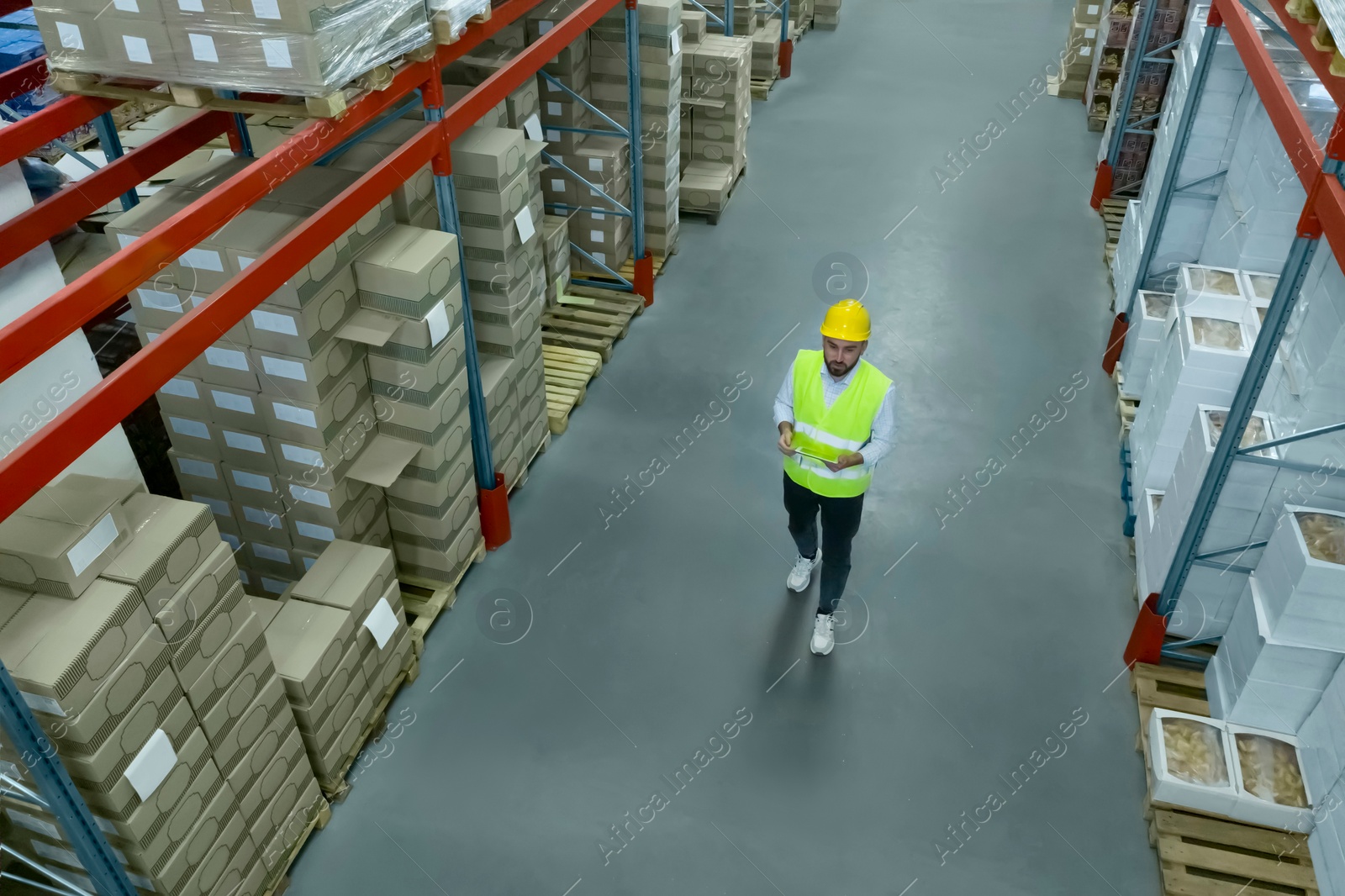 Image of Man with tablet working at warehouse, above view. Logistics center