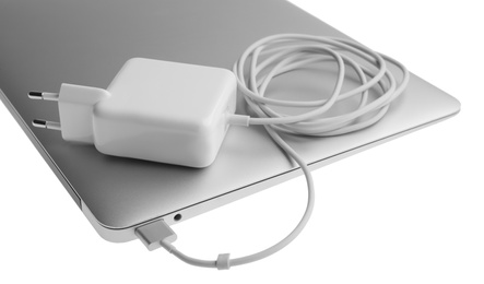 Photo of Laptop and charger on white background, closeup. Modern technology