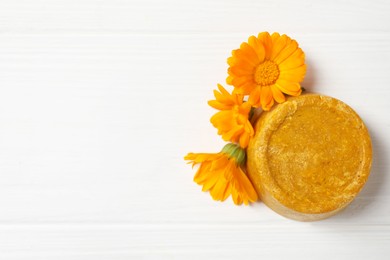 Photo of Yellow solid shampoo bar and flowers on white wooden table, flat lay. Space for text