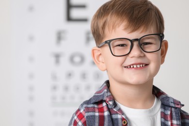 Photo of Little boy with glasses against vision test chart
