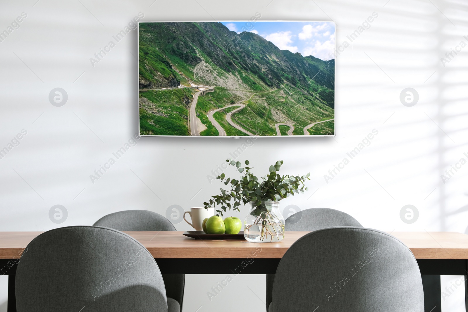 Image of Modern wide screen TV on white wall in room with stylish furniture 