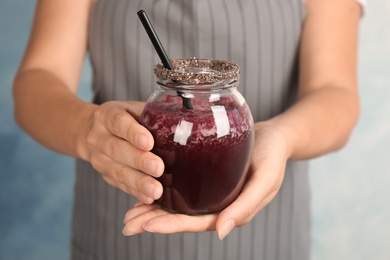 Photo of Woman holding jar of delicious acai juice, closeup