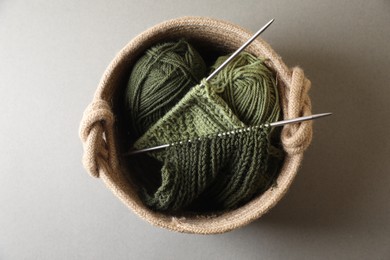 Green knitting, needles and soft yarns on light background, top view